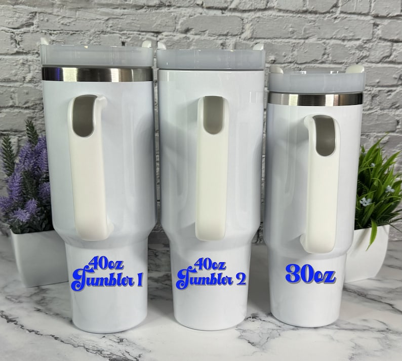 May include: Three white stainless steel travel mugs with blue text. The mugs are 40 oz, 40 oz, and 30 oz. The mugs have a handle and a lid.