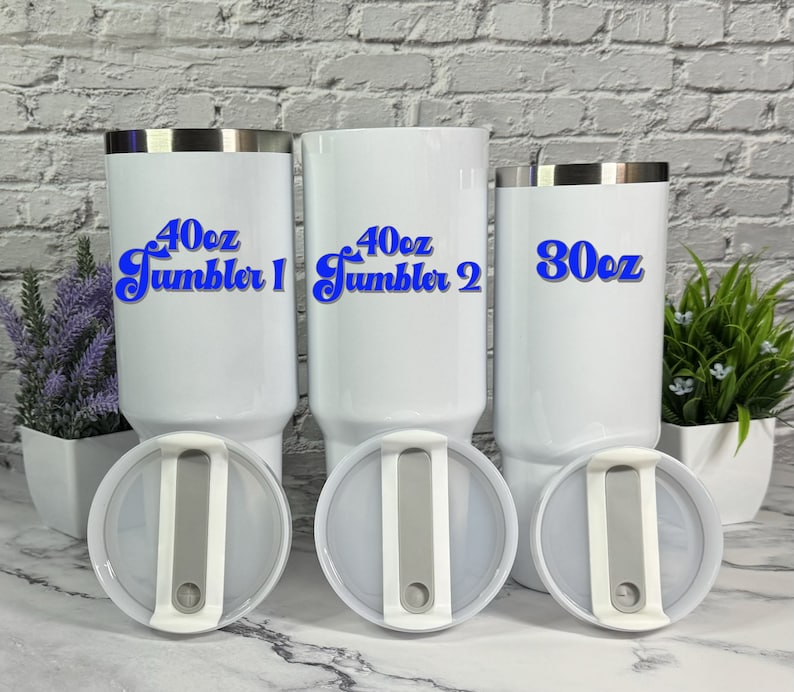May include: Three white stainless steel tumblers with lids. The tumblers are labeled with blue text: "40oz Tumbler 1", "40oz Tumbler 2", and "30oz".