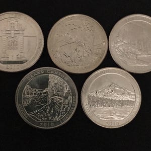 May include: Five silver United States quarters, each with a different design. The quarters feature images of national parks and landmarks, including the Grand Canyon and Mount Hood. Each coin is dated 2010.
