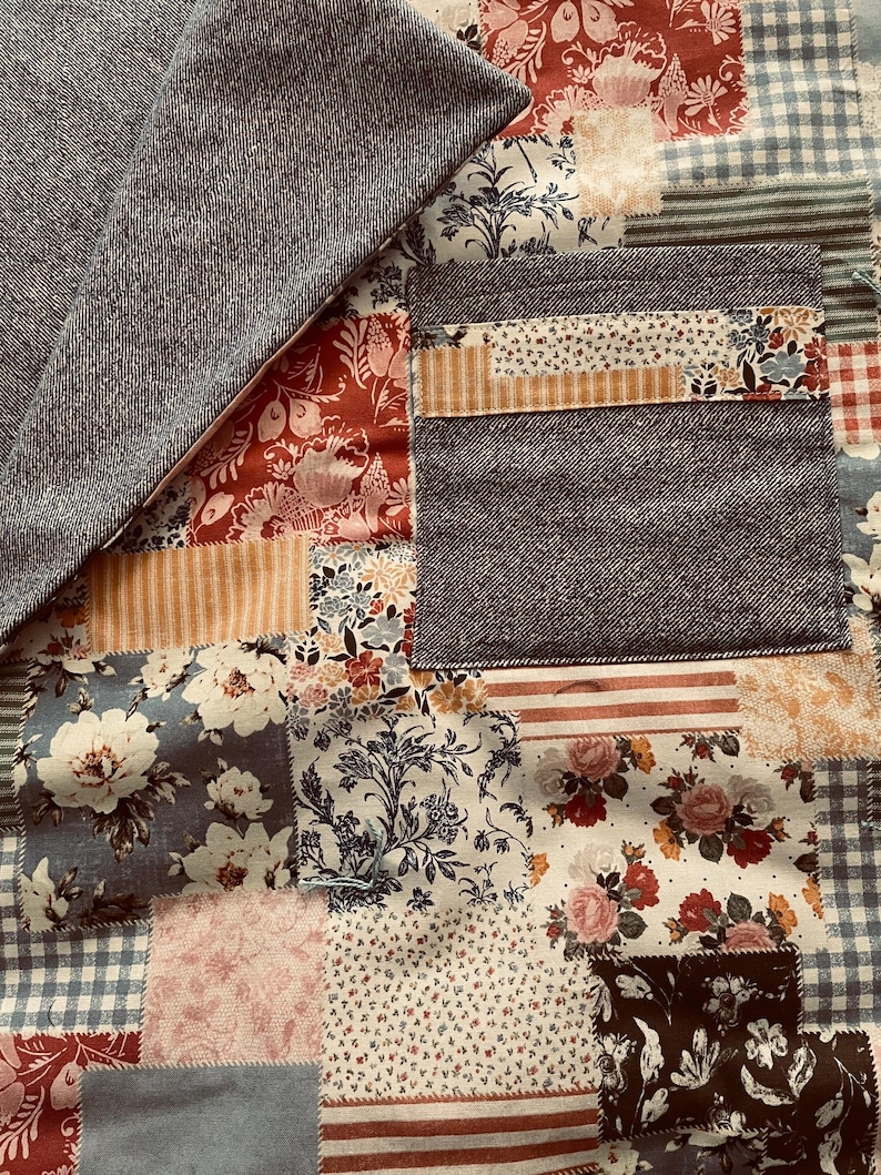 Puede incluir: Una colcha de retazos con una variedad de patrones florales en tonos de azul, rojo y blanco. La colcha est&aacute; hecha de diferentes telas, incluyendo denim, algod&oacute;n y lino.