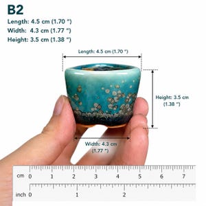 May include: A small ceramic pot with a teal and dark blue gradient glaze featuring circular patterns. The pot is labeled B2 and measures 1.70 inches in length, 1.77 inches in width, and 1.38 inches in height as indicated by the visible text.
