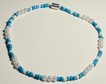 May include: A white and blue beaded necklace with a magnetic clasp. The necklace features white pearls and blue and turquoise beads.
