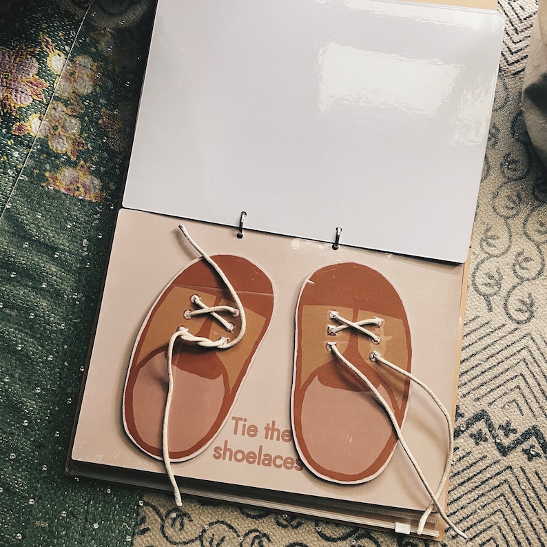 May include: A brown and beige children's book with two brown shoes with white laces. The text on the book says "Tie the shoelaces".