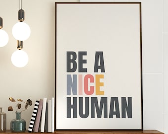 May include: A wooden shelf with a framed print that reads "BE A NICE HUMAN" in colorful letters. The print is hanging above a vase with dried branches and two glass bottles. There are also three books stacked on the shelf.