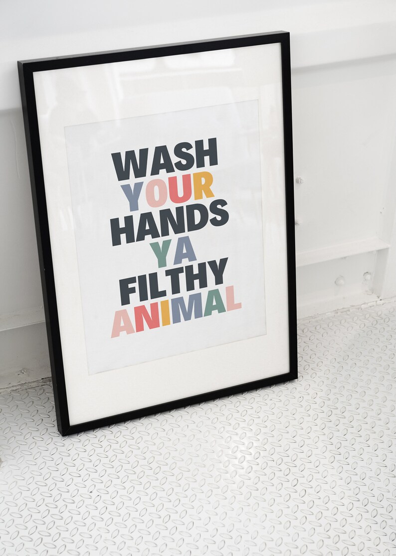 May include: A black framed print with the text "Wash your hands ya filthy animal" in colorful letters.