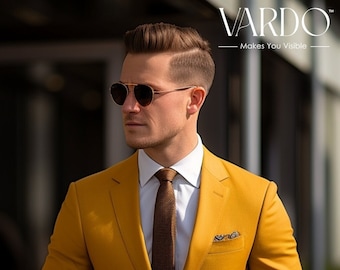 May include: A man wearing a mustard yellow suit with a brown tie and a white shirt. He is wearing sunglasses and has his hand in his pocket.