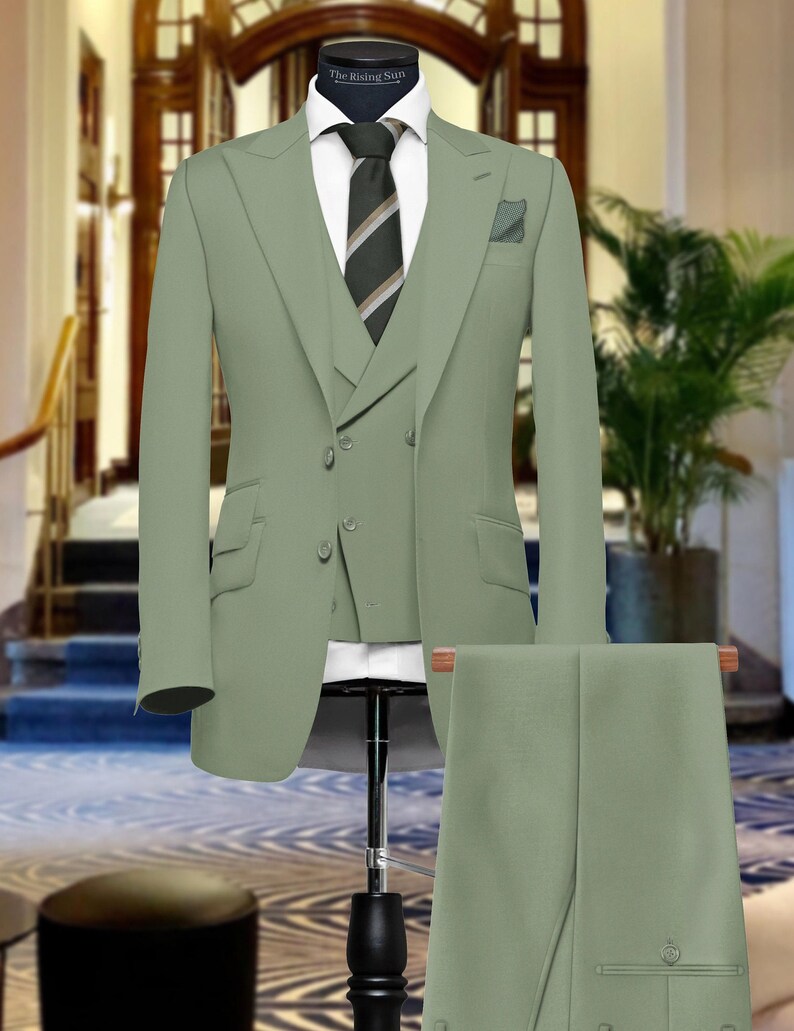 May include: A three-piece suit in a light green color. The suit includes a jacket, vest, and pants. The jacket has a double-breasted closure and a notch lapel. The vest has a single-breasted closure. The pants have a flat front.