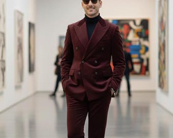 May include: A burgundy double-breasted suit with a black turtleneck. The suit has a velvet texture and is worn with sunglasses. The person is standing in an art gallery.