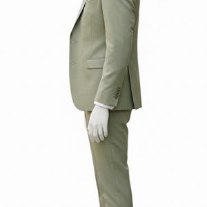 K&ouml;nnte beinhalten: Ein hellgr&uuml;ner Anzug an einer Schaufensterpuppe. Der Anzug umfasst einen Blazer mit Einstecktuch und passender Krawatte sowie eine Hose. Die Schaufensterpuppe tr&auml;gt ein wei&szlig;es Hemd und braune Lederschuhe. Der Anzug ist einfarbig.
