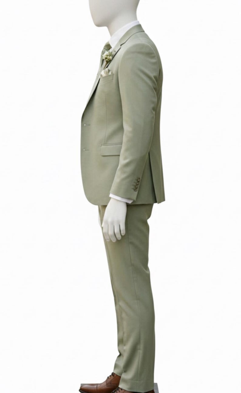 K&ouml;nnte beinhalten: Ein hellgr&uuml;ner Anzug an einer Schaufensterpuppe. Der Anzug umfasst einen Blazer mit Einstecktuch und passender Krawatte sowie eine Hose. Die Schaufensterpuppe tr&auml;gt ein wei&szlig;es Hemd und braune Lederschuhe. Der Anzug ist einfarbig.