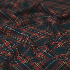 Könnte beinhalten: Nahaufnahme eines Stoffes mit klassischem Karomuster. Der Stoff hat einen dunkelblauen Hintergrund mit einem rot, weiß und gelb karierten Design. Der Stoff ist drapiert und zeigt Textur und Falten.