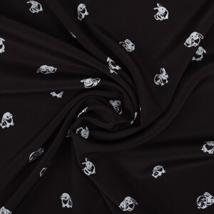 May include: Black fabric with a repeating pattern of white cartoon bunnies in various poses. The fabric is draped, showing folds and shadows, and the bunnies are scattered across the surface.