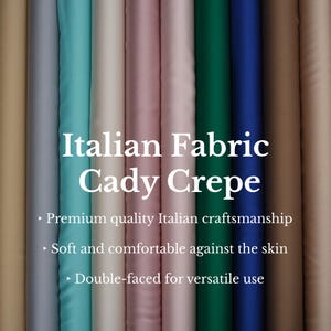 Op de afbeelding: Een display van verschillende gekleurde Cady Crêpe stoffen rollen. De afbeelding bevat de tekst "Italian Fabric Cady Crepe". De stof is verkrijgbaar in tinten beige, grijs, teal, roze, groen en blauw. De tekst vermeldt ook Italiaans vakmanschap van topkwaliteit.