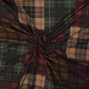 May include: A fabric with a patchwork design featuring different plaid patterns in shades of brown, green, and red.
