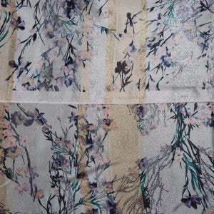 May include: A white fabric with a silver and gold striped pattern and a floral print in shades of pink, blue, and green.