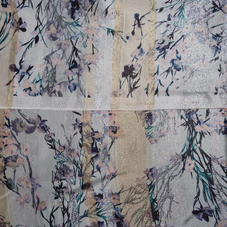 May include: A white fabric with a silver and gold striped pattern and a floral print in shades of pink, blue, and green.