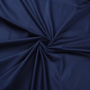 May include: Close-up of a smooth, dark blue fabric with a soft, flowing texture.