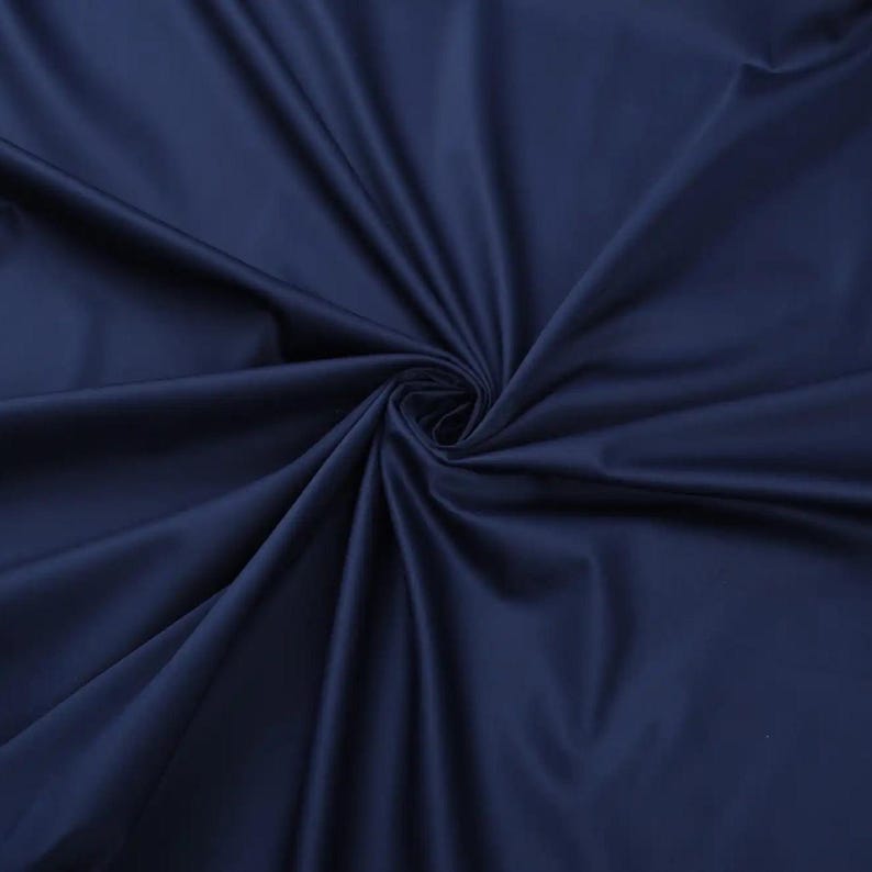 May include: Close-up of a smooth, dark blue fabric with a soft, flowing texture.