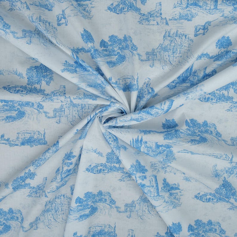 May include: White fabric with a blue and white toile pattern featuring a repeating design of trees, houses, and a river. The fabric is folded and draped.