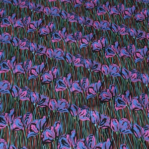May include: A black fabric with a repeating pattern of pink and blue stylised flowers. The flowers are outlined in black and have a white centre.