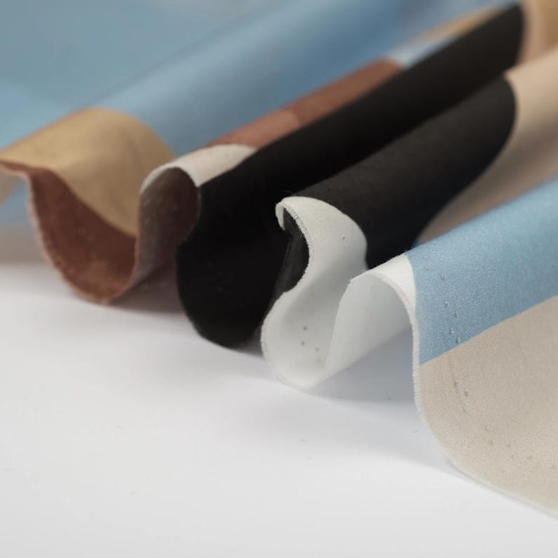 Puede incluir: Primer plano de una tela con rayas de diferentes colores, incluyendo azul, marr&oacute;n, negro y blanco. La tela tiene una superficie texturizada y est&aacute; doblada.
