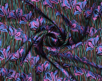 May include: Black fabric with a repeating pattern of pink and blue stylized iris flowers on a black background with green and red lines.
