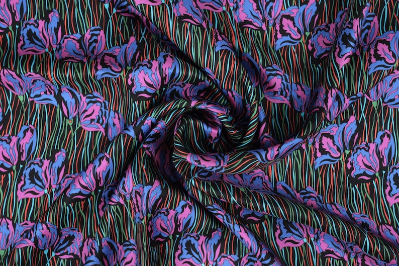 May include: Black fabric with a repeating pattern of pink and blue stylized iris flowers on a black background with green and red lines.