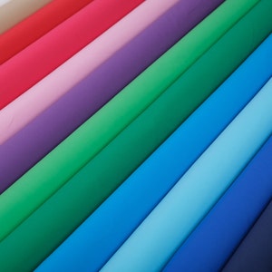 May include: A collection of fabric swatches in various colors, including beige, red, pink, purple, green, blue, light blue, and dark blue. The fabric swatches are arranged in a diagonal pattern, creating a rainbow effect.
