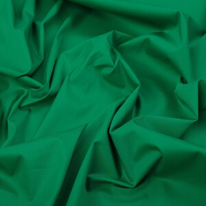 May include: A close-up of a smooth, green fabric with soft folds and wrinkles.