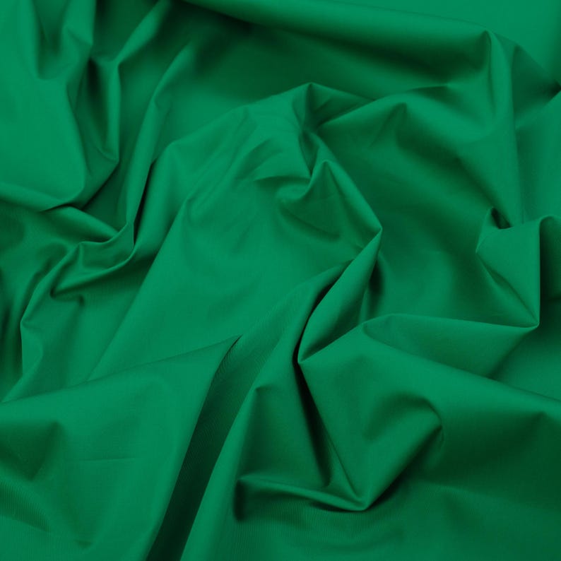 May include: A close-up of a smooth, green fabric with soft folds and wrinkles.