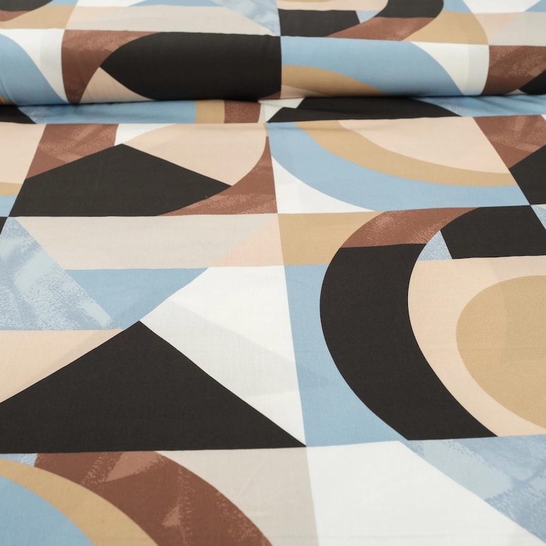 Puede incluir: Tela geom&eacute;trica con un patr&oacute;n repetitivo de c&iacute;rculos, cuadrados y tri&aacute;ngulos en tonos marrones, beige, azules y negros.