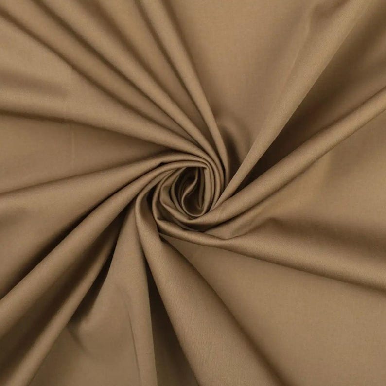 May include: A close-up of a smooth, brown fabric with a soft, subtle sheen. The fabric is folded and draped, creating a luxurious and elegant look.