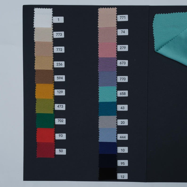 May include: A color swatch card featuring fabric samples in various colors, including white, beige, brown, yellow, green, red, teal, blue, and purple. Each color is labeled with a number. A piece of teal fabric is in the upper right corner.