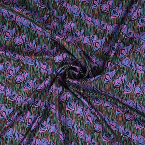 May include: A black fabric with a repeating pattern of pink and blue flowers with green stems. The fabric is folded and draped.