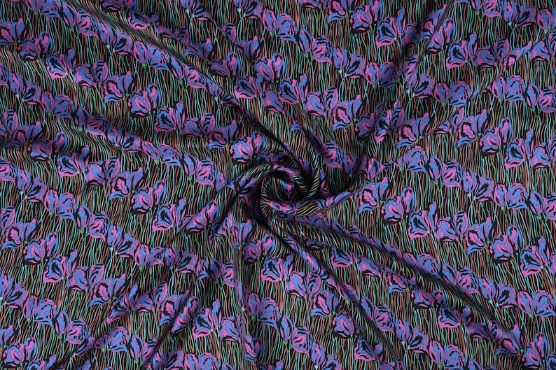 May include: A black fabric with a repeating pattern of pink and blue flowers with green stems. The fabric is folded and draped.