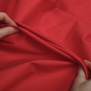 May include: Close-up of a bright red fabric, showing the texture and drape of the material.
