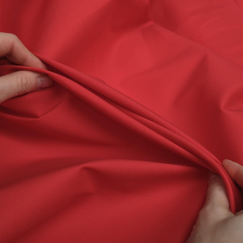 May include: Close-up of a bright red fabric, showing the texture and drape of the material.