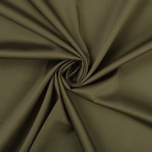 May include: A close-up of a smooth, dark green fabric. The fabric is folded and draped, showing its texture and color.
