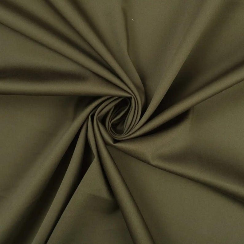 May include: A close-up of a smooth, dark green fabric. The fabric is folded and draped, showing its texture and color.