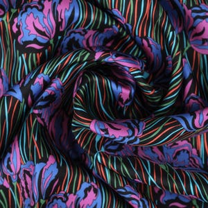 May include: Black fabric with a colourful floral pattern. The fabric features pink, blue and green flowers on a black background with thin, colourful stripes.