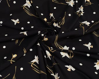 May include: Black fabric with a white polka dot pattern and white floral print. The fabric is folded and draped.