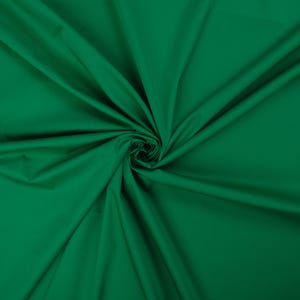 May include: A close-up of a deep green fabric with a smooth texture. The fabric is folded and draped, creating a soft, flowing look.