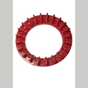 Op de afbeelding: Een rode plastic ring met een reeks verhoogde ribbels rond de buitenrand. De ring is ontworpen om te worden gebruikt als een decoratief accent of een functioneel onderdeel.
