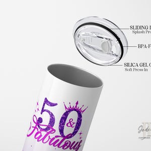 May include: A white stainless steel tumbler with a purple and pink glitter design that says "50 & Fabulous". The tumbler has a clear, sliding lid with a silicone O-ring.
