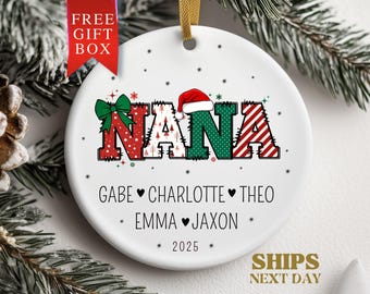 May include: White ceramic Christmas ornament with the word "NANA" in festive colors and a Santa hat. Below are names and the year 2025. A red ribbon says "FREE GIFT BOX".