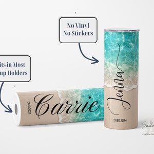 Puede incluir: Dos vasos de acero inoxidable con un dise&ntilde;o de playa. Los vasos est&aacute;n personalizados con los nombres "Carrie" y "Jenna". El texto "CABO 2024" est&aacute; impreso en la parte inferior de cada vaso. Los vasos se anuncian como "Sin vinilo, sin pegatinas".