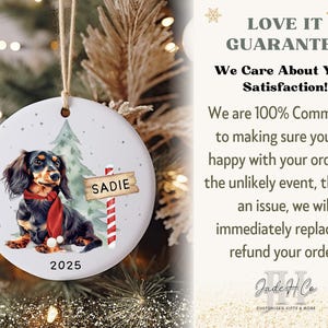 May include: A round ceramic Christmas ornament featuring a dachshund wearing a red scarf, with the name "Sadie" on a sign. The ornament has a Christmas tree and the year 2025. The text "LOVE IT GUARANTEE" is also visible.