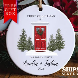 May include: White round Christmas ornament with a red door, two green pine trees, and the text "First Christmas at 248 Joran Drive Emilia + Joshua 2024".