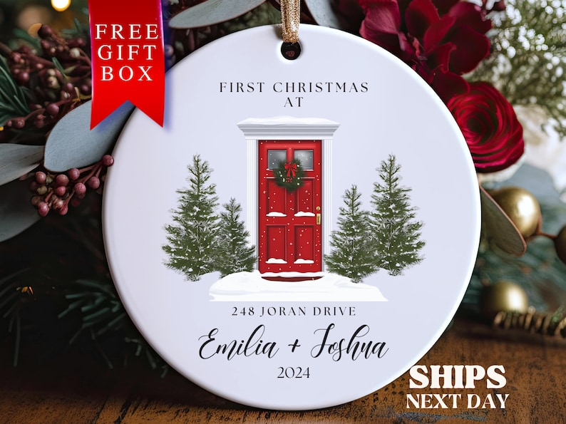 May include: White round Christmas ornament with a red door, two green pine trees, and the text "First Christmas at 248 Joran Drive Emilia + Joshua 2024".