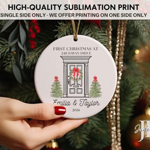 May include: White ceramic Christmas ornament with a black and white illustration of a house door with a wreath and two small Christmas trees. The text "First Christmas at 248 Joran Drive" is above the door and "Emilia & Taylor 2024" is below the door.